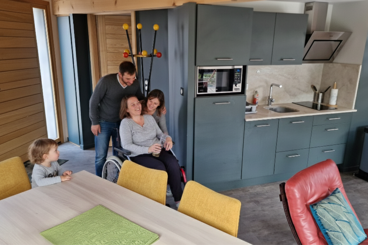 Personne en fauteuil roulant circulant facilement dans le salon spacieux et adapté du gîte La Lanterne.