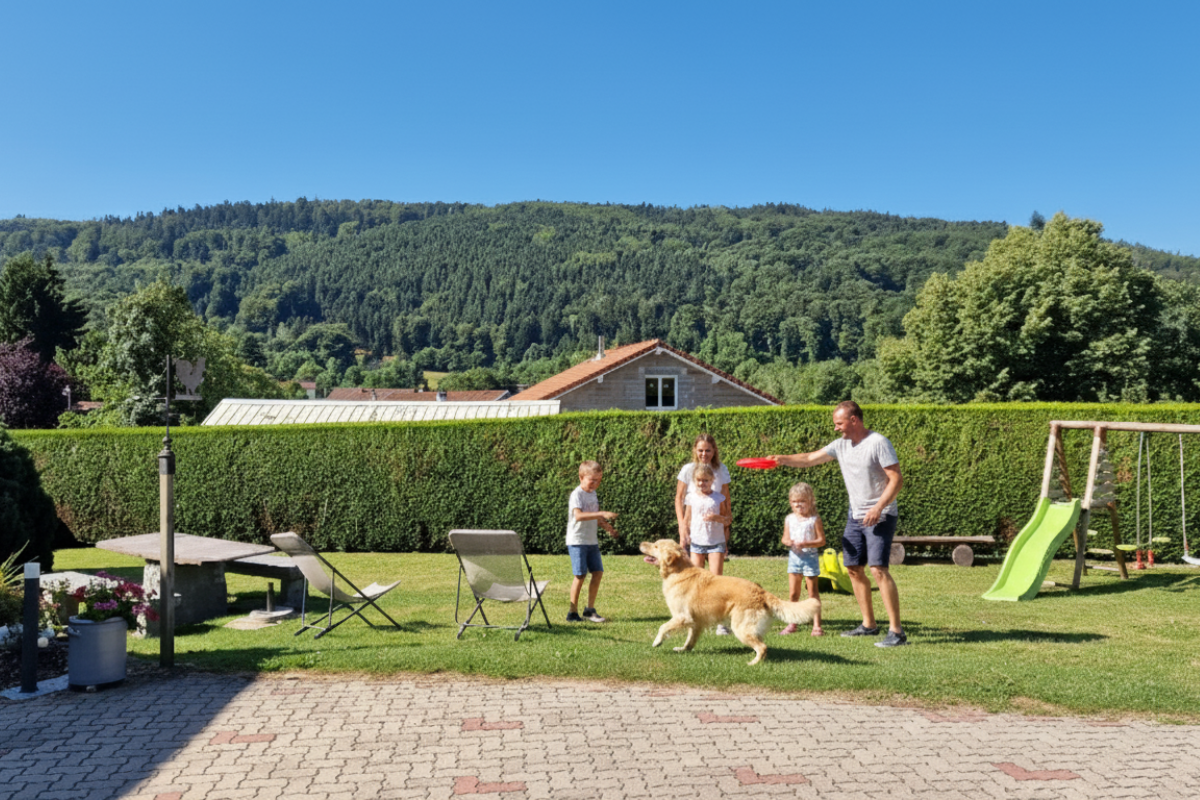 Famille jouant avec leur chien dans le grand jardin du gîte Le Chalet au Domaine de la Répandise.