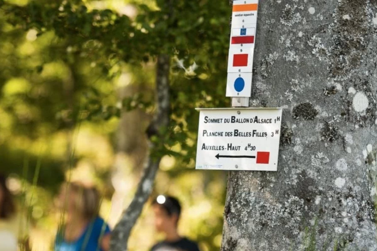 Panneau de signalisation de randonnée indiquant les distances et temps de parcours autour de Laveline-du-Houx.